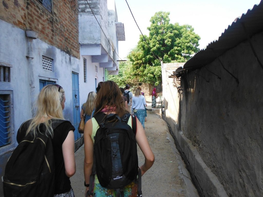 group walking in small allyway in india