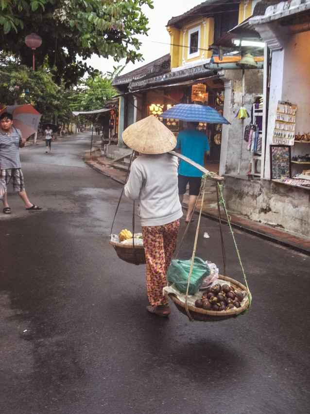 old lady carrying 2 fruit baskets in Hoi An