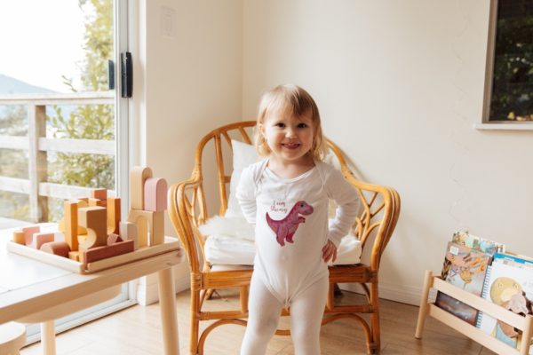toddler wearing pink dino baby bodysuit